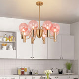 Gloral Chandelier in a white kitchen, combining pink glass globes and gold metal for a modern luxury lighting statement.
