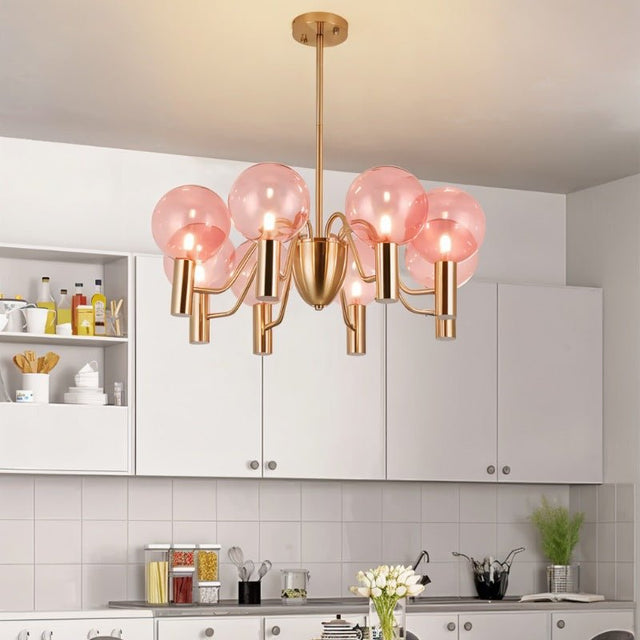 Gloral Chandelier in a white kitchen, combining pink glass globes and gold metal for a modern luxury lighting statement.