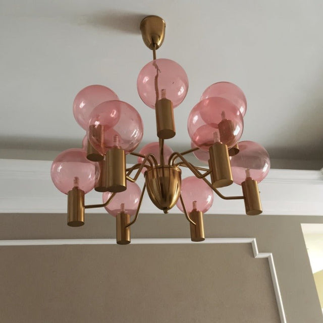 Ceiling-mounted Gloral Chandelier with pink glass bulbs and gold arms, enhancing indoor lighting with a modern aesthetic.