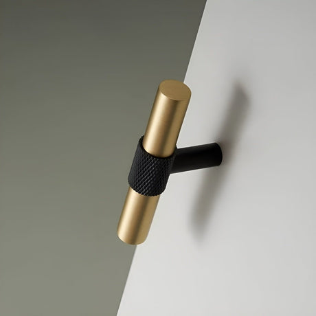 "Close-up of a brushed gold and black knob with knurled detailing on a light surface."