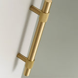 "Close-up of a brushed gold pull bar handle with knurled detailing on a light-colored surface."