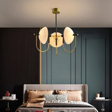 "Modern gold three-light chandelier with frosted glass orbs hanging over a bed in a bedroom."