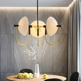 "Modern gold three-light chandelier with frosted glass orbs hanging over a dining table."