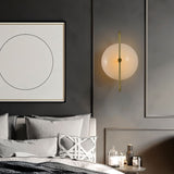 "Brass wall lamp with frosted glass globe in a minimalist bedroom setting, providing a soft, ambient glow."