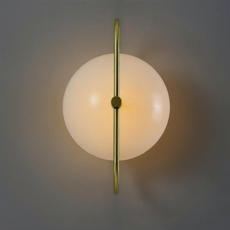 "Close-up of a wall lamp with a brass frame and frosted glass globe, showing its symmetrical design and warm, diffused light."
