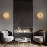 "Pair of brass wall lamps with frosted glass globes flanking a modern fireplace in a living room, providing symmetrical lighting."