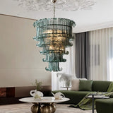 "A tiered glass chandelier in a modern living room with a green sofa."