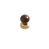 "A modern round knob featuring a wooden top and a golden metallic base."