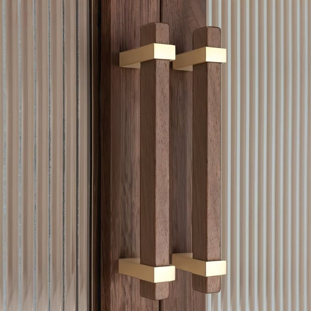 "Modern wooden pull bars with gold metallic brackets on a cabinet with fluted glass doors."