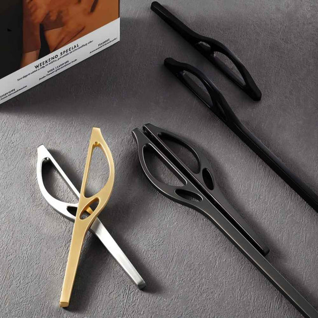"Modern curved pull bar handles in gold, silver, and black finishes, displayed on a grey surface."