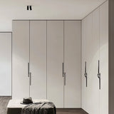 "Black zinc alloy pull bars with flowing curves on a white wardrobe."
