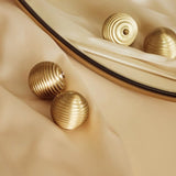 "Set of gold brass ribbed knobs on a cream fabric with a gold-trimmed mirror."