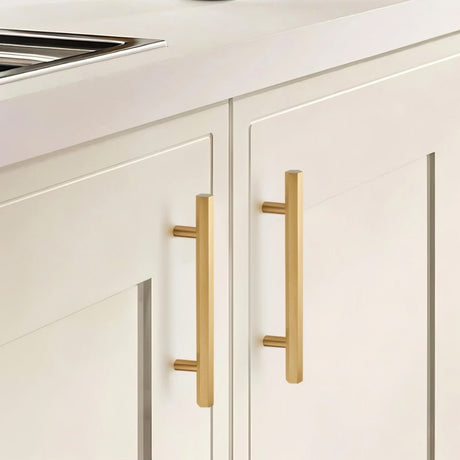  "Modern brass rectangular pull bar handles with cylindrical mounts on white shaker kitchen cabinets."