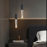 "Pair of modern pendant lights with elongated crystal diffusers and metal frames in a contemporary bedroom."