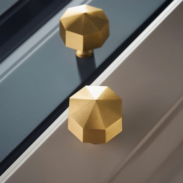 "Two gold brass hexagonal knobs on two-tone grey cabinet doors."