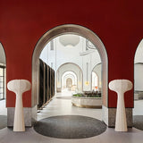 "Sculptural floor lamps with a minimalist design, positioned in a grand interior with arched architecture, featuring flared tops and streamlined silhouettes, crafted from high-quality material."