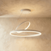 Modern black LED pendant light with circular rings suspended above bedroom with white walls and dark headboard.