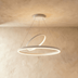 Black modern pendant light with concentric circular rings suspended in contemporary living room with green plant and beige so