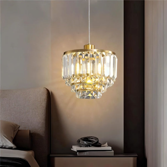 "A tiered crystal pendant light with a brass frame, hanging in a bedroom."