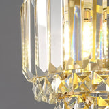 "Close-up of a tiered crystal pendant light with a brass frame, showing the intricate details of the crystal elements and their light refraction."