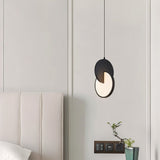 "A modern black pendant light with overlapping discs in a bedroom with a plant."