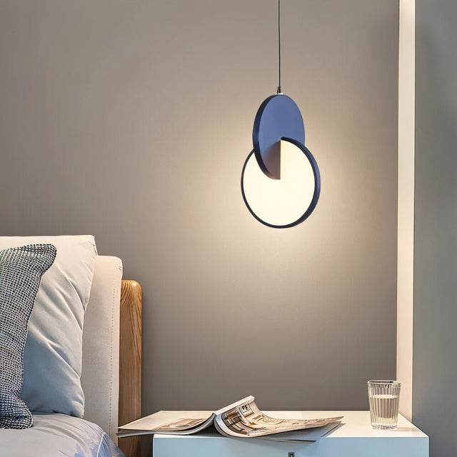 "A modern blue pendant light with overlapping discs in a bedroom setting."