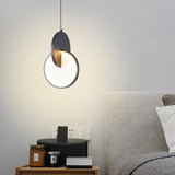 "A modern dark pendant light with overlapping discs in a bedroom above a nightstand."