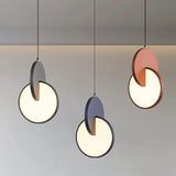 "A set of modern pendant lights with overlapping discs in various colors, lit against a light background."