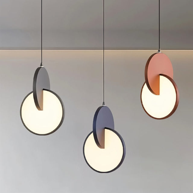 "A set of modern pendant lights with overlapping discs in various colors, lit against a light background."