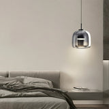 "A modern pendant light with a smoked glass dome shade hanging in a bedroom."
