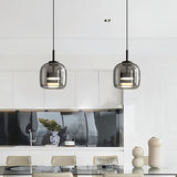 "Two modern pendant lights with smoked glass shades hanging over a dining table."