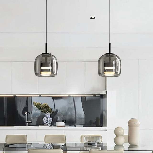 "Two modern pendant lights with smoked glass shades hanging over a dining table."