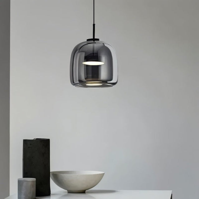 "A modern pendant light with a smoked glass shade hanging in a minimalist setting."
