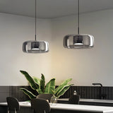 "Two modern pendant lights with smoked glass dome shades hanging in a kitchen."