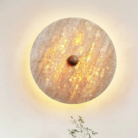 "Close-up of the Illura Wall Lamp made from travertine stone, emitting a soft, diffused backlight that creates a warm, glowing effect."