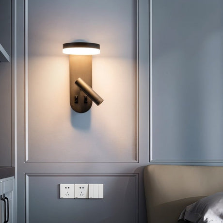 "A black wall lamp with an LED panel and a spotlight, installed above a light switch, next to a beige headboard."