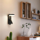"A black wall lamp with an LED panel and a spotlight, installed on a wall with shelves, plants, and decor."