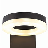 "A close-up of the illuminated LED panel of a black wall lamp with a circular design."