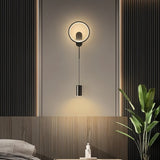 "A modern black wall lamp with a circular design and adjustable light source in a contemporary bedroom."