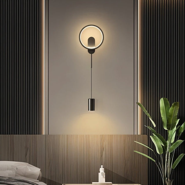 "A modern black wall lamp with a circular design and adjustable light source in a contemporary bedroom."
