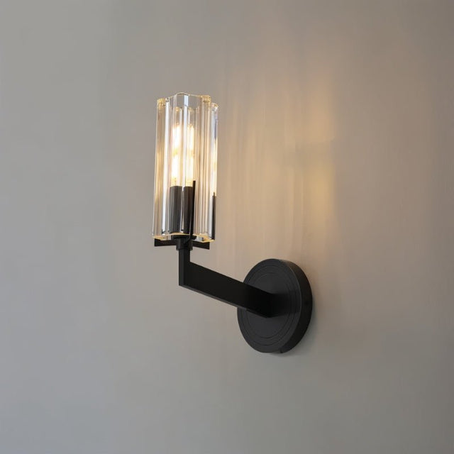 "A modern black wall lamp with a minimalist yet luxurious design, featuring a sleek iron base and a cylindrical glass shade casting a soft, ambient light."