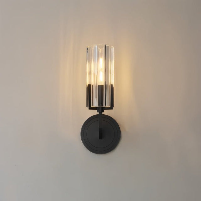 "A modern black wall lamp with a minimalist yet luxurious design, featuring a sleek iron base and a cylindrical glass shade casting a soft, ambient light, isolated on a white background."