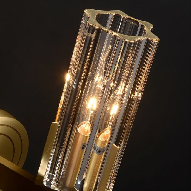 "Close-up of a modern brass wall lamp with a matte gold finish and cylindrical glass shade, showcasing its intricate details and luxurious design."
