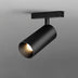 Black cylindrical track light with warm LED glow mounted on gray background.