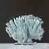 Pale blue textured coral figurine on a clear acrylic base against a dark gray background.