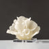 Cream-colored abstract sculptural figurine on clear acrylic base against dark gray background.