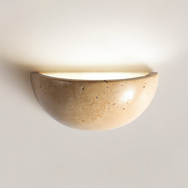 "Close-up of a modern, semi-circular wall lamp made of yellow travertine, showing its smooth surface and the warm light it emits."