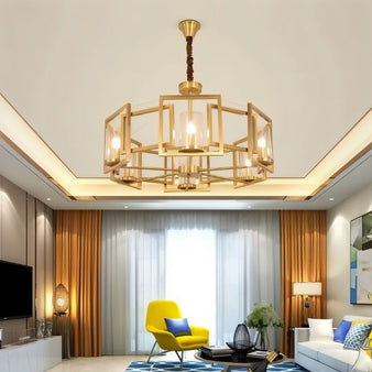 "A modern chandelier with a geometric brass frame and cylindrical glass shades, hanging in a living room with bright furniture and curtains."