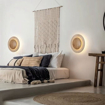 "Pair of sculptural wall lamps with travertine stone and wood in a modern bedroom setting."