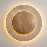 "Circular wall lamp with a travertine stone frame and a wooden center, emitting a soft, ambient glow."